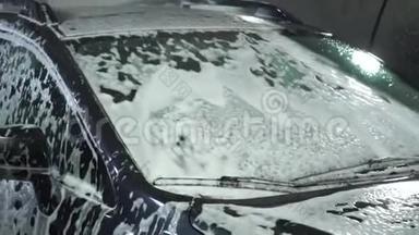 洗车。 洗车机清洗汽车。 车上覆盖着白色的冲洗泡沫.. 特写镜头。
